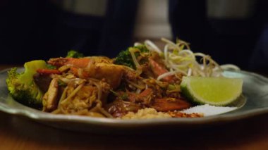 Renkli Tayland sokak yemekleri. Lime ve Tofu ile geleneksel Pad Thai 'nin yakın çekimi. Otantik Tayland yemekleri bir restoranda servis ediliyor. Yemeğin başlangıcı. Çok güzel servis edilmiş bir tabak.