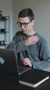 Ofiste omuz ağrısı. Boyun ağrısı, ofis sendromu, kas ağrısı olan ve uzun süre bilgisayar laptopuyla uğraşan bir adam. Dikey video