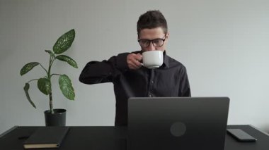 Adam terasta bir masaya oturur ve dizüstü bilgisayarını açar. Ellerine yakın çekim, tanınmayan bir kişi.