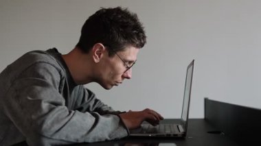 Masada kötü duruşu olan bir adam oturuyor. Bilgisayarda uzun saatler geçirdikten sonra geri dönmüş. Uzak çalışma sırasında uygunsuz ergonomik