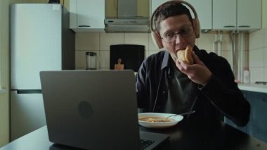 Masada yemek yerken kulaklıkla oynayan genç adam, online oyun takıntısı kavramı