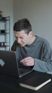 Evdeki yorgun adamın bilgisayarın başında otururken gözlük çıkarması, dijital göz yorgunluğu ya da uzun ekran zamanının yorgunluğunu göstermesi. Ofis sendromu konsepti. Dikey video
