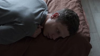 Yatakta yatan bunalımlı bir adam. Genç erkek uyumaya çalışıyor. Huzursuz, endişeli, uykusuz, şaşkın, uykusuzluk çeken, uyku bozukluğu çeken bir adam..