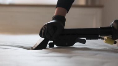 Yatak temizleme servisi. Siyah eldivenler giyerek temiz yatak yüzeyi oluşturmak için elektrikli süpürge kullanan profesyonel bir kadın..
