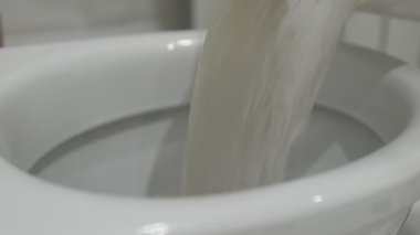 Profesyonel yatak temizliğinden sonra klozete kirli su dökülüyor. Bulanık sıvı, gizli tozu, alerjik maddeleri ve yatak örtüsünden toplanmayı temsil ediyor. Temizlik reklamları, ev bakımı içeriği ve sağlık farkındalığı videoları için ideal.