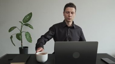 Adam terasta bir masaya oturur ve dizüstü bilgisayarını açar. Ellerine yakın çekim, tanınmayan bir kişi.