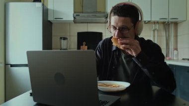 Oyun bağımlısı bilgisayar önünde yemek yerken kulaklığı açık, oyun oturumunu durduramıyor.