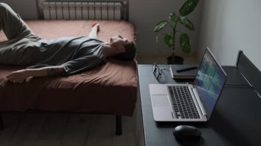 Serbest patinaj. Yorgun bir adam ev ofisinin loş köşesinde dizüstü bilgisayar ve gözlüklerin yanında uzanmış, zihinsel yorgunluğu gösteriyor.