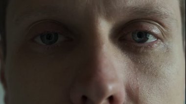 Göz yaşı damlasıyla insan gözü, aşırı yakın plan. Gözlerinden yaşlar akan duygusal bir adam. Umutsuzluk içinde ağlayan adamın dramatikliği.