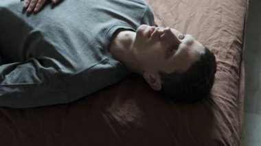 Yatakta yatan bunalımlı bir adam. Genç erkek uyumaya çalışıyor. Huzursuz, endişeli, uykusuz, şaşkın, uykusuzluk çeken, uyku bozukluğu çeken bir adam..