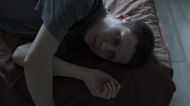 Psikolojik bozukluklar ve sorunlar. Psikolojik yardım kavramı. Bunalımlı bir adam yatakta yatar ve duygusuz bir şekilde tavana bakar.