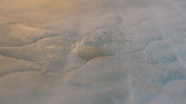 Görünür siyah lekeli ve nemli kirli yatak kumaşının yakın çekimi. Püskürtme şişesi iyice ovmadan önce temizleme solüsyonu uygular. Hijyen kavramları, leke çıkarma ve reklam metinleri için ideal.