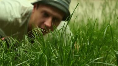 Kapüşonlu titiz bir adam özel bahçede uzun yeşil çimenleri makasla kesiyor. Evin yakınındaki çimleri budarken dikkatli ol. Açık hava mevsimlik bahçe işleri.