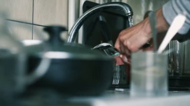 Erkek eli, çatal ve kaşıkları sünger ve köpükle yıkıyor.