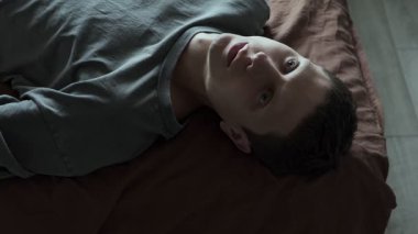 Psikolojik bozukluklar ve sorunlar. Psikolojik yardım kavramı. Bunalımlı bir adam yatakta yatar ve duygusuz bir şekilde tavana bakar.