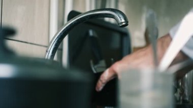 Kirli bulaşıklarla dolu lavaboda elleri temizleyen bir tabak.