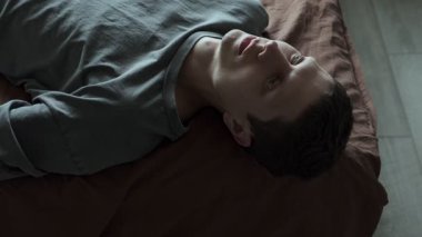 Psikolojik bozukluklar ve sorunlar. Psikolojik yardım kavramı. Bunalımlı bir adam yatakta yatar ve duygusuz bir şekilde tavana bakar.