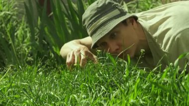 Çimleri biçmek için elinde makasla eğilen bir adam, mizahi, abartılı bir bahçe sahnesinde mükemmel bahçe bakımıyla ilgili takıntıları parodiliyor.