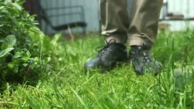 Çim biçme makinesi olan bahçıvan. Arka bahçedeki çim biçme makinesiyle yakın plan. Bahçe bakımı ve bahçe bakımı kavramı