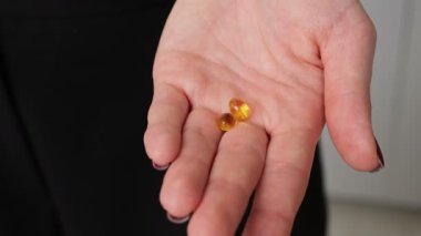 İki tane vitaminli ve takviyeli softgel kapsülü. Koyu arkaplanda yakın plan sağlık kavramı