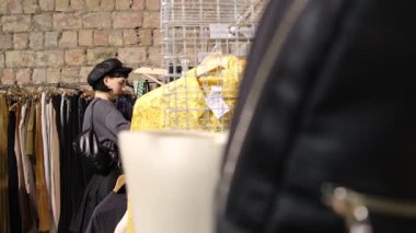 İkinci el dükkanında şık giyinen genç bir kadın. Sürdürülebilir moda ve çevre dostu alışveriş