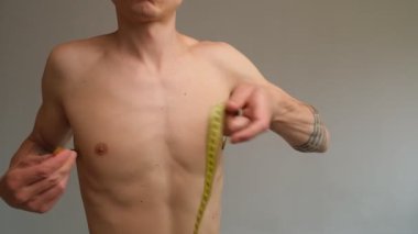 Göğsünü bantla yakından ölçen bir adam. Fitness izleme, kas kazanma ya da kilo verme motivasyonu