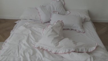 Yatak odasında beyaz çarşaflar ve dekoratif yastıklarla yapılmamış yatak. Minimalist iç mekanda sabah sahnesi.