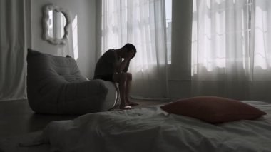 Çaresiz bir adam, ilişkisinin bozulması ve apartmandaki kişisel çöküşün yükü altında öylece oturur..