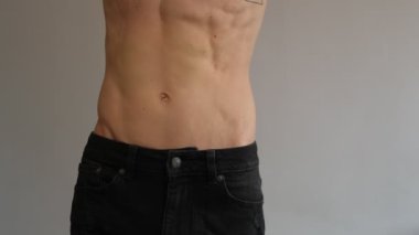 Formda bir genç adam kaslı ve ince bel gösteriyor. Kotlu sağlıklı erkek gövdesinin yakın çekimi. Fitness ve vücut bakımı