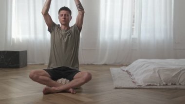 Özenli nefes alma meditasyonu uygulayan genç adam evde iç huzur için nefes alma egzersizi yapıyor.