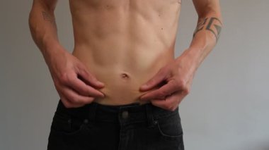 Düşük vücut yağlarını göstermek için göbek derisini çimdikleyen bir adam.