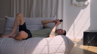 Modern bir dairede koltukta uzanmış duygusal oyunlar oynayan bir adam. Modern ekran yaşamı