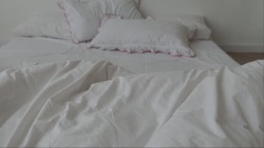 Beyaz çarşaflı yapılmamış yatak. Yapılmamış boş yatak. Sabahları dağınık beyaz yatak odasını kapatıyoruz.