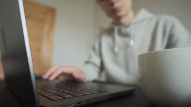 İçişleri Bakanlığı 'ndaki bir bardaktan kahvesini yudumlayan adam bilgisayarlı bir masanın arkasında. Freelancer rutini. Gün ışığı, ev içi..