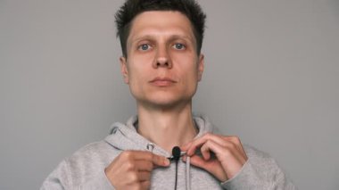 Kapüşonuna lavalier mikrofon takan adama yaklaş. Bir podcast, vlog veya televizyon için röportaj kaydetmeye hazırlanılıyor