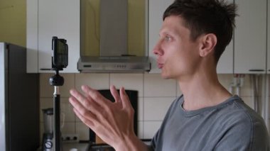 Genç bir adam mutfağında motive edici bir video blogu kaydediyor, izleyicileri kişisel büyüme ve günlük alışkanlıklarda tutarlılık yolunda küçük adımlar atmaya teşvik ediyor..