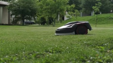 Robot çim biçme makinesi yerleşim alanında çalışıyor. Otomatik çim biçme ve zahmetsiz çim bakımı için modern akıllı aygıt.
