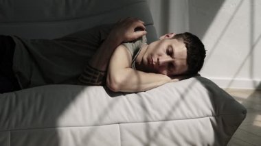 Yorgun adam yüzünü kapatıyor. Duygusal çöküntü, dramatik güneş ışığı altında.