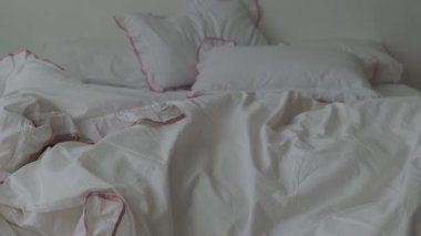 Beyaz çarşaflı yapılmamış yatak. Yapılmamış boş yatak. Sabahları dağınık beyaz yatak odasını kapatıyoruz.