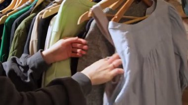 İkinci el mağazası. Askılarda kıyafet arayan genç kadınların yakın plan fotoğrafları.