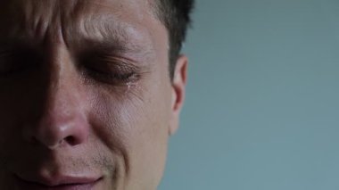 Gözleri kapalı genç bir adamın yanağından süzülen göz yaşının aşırı yakın çekimi. Görüntü, acıyı, kırılganlığı ve insan kırılganlığını vurgulayan hassas bir anı yakalıyor..