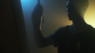 Sinema sehpasında resim yapan genç bir erkek sanatçı. Huysuz sarı ve mavi arkaplan, yan görüş.