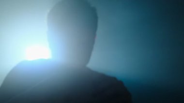 Acemi boksör, siluette yumruklar eğitiyor. Genç adam boks hareketlerini sinematik mavi ışıkta yapıyor.