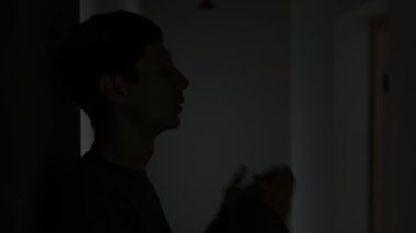Koridorda yalnız bir adamın silueti ayrılıktan sonra elleriyle yüzünü gizliyor..