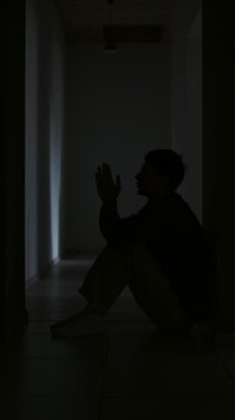 Umutsuzluk ve üzüntü genç adam karanlık koridorda tek başına dua ediyor hayal kırıklığını ve umutsuzluğu hissediyor.