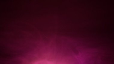 Siyah arkaplanda dönen mor dumanın yavaş çekim görüntüsü. Müzik, meditasyon ve görseller için soyut düş gibi sis. Yumuşak sis zarif bir atmosfer arkaplanı oluşturuyor.