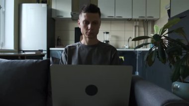 Gerçek hayatta ofis sahnesi, günlük kıyafetlerle serbest çalışan mutfak kanepesinde dizüstü bilgisayarda çalışan otantik iş hayatı tarzı..