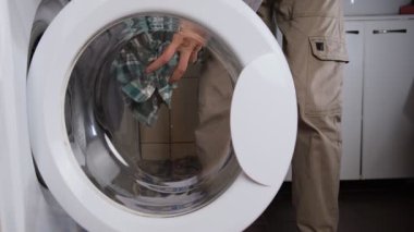 Bir el açıcı çamaşır makinesinin gerçekçi yaşam tarzı görüntüleri ve içine çamaşır koymak, yan manzara ev çamaşırları rutini