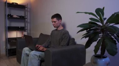 Dizüstü bilgisayarda çalışan genç bir serbest yazar kanepenin üzerinde otantik bir yaşam tarzıyla oturuyor..