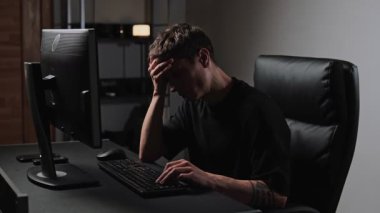 Gece geç saatlerde bilgisayar masasında çalışırken yorgun düşmüş bir adam iş stresi ve ofis yorgunluğu kavramı..